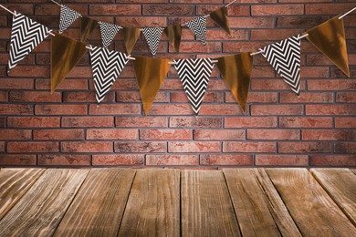 Image of Empty wooden table and decorative bunting flags hanging on brick wall