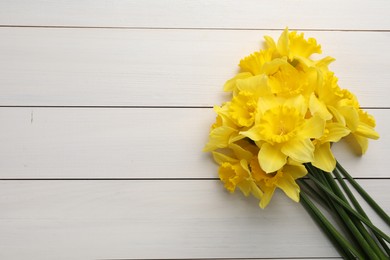 Photo of Beautiful daffodil bouquet on white wooden table, top view. Space for text