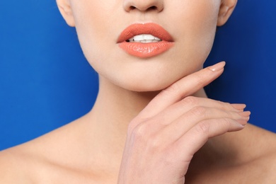 Photo of Young woman wearing beautiful lipstick on color background, closeup