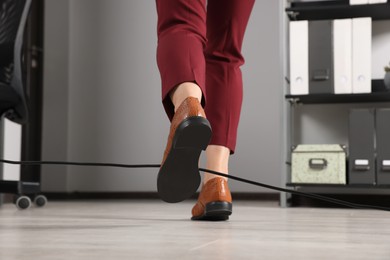 Photo of Woman tripping over cable in office, closeup