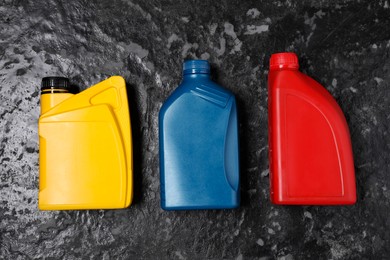 Motor oil in different canisters on black table, flat lay