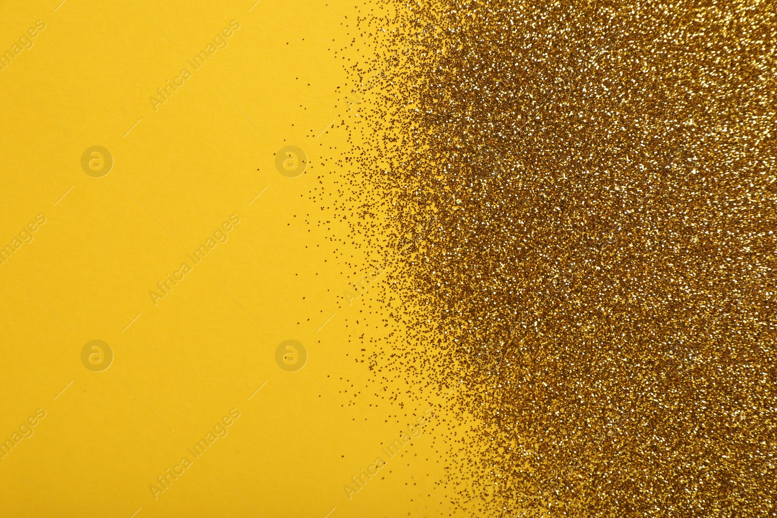 Photo of Shiny golden glitter on yellow background, top view. Space for text