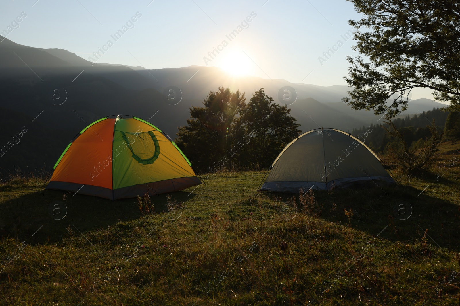 Photo of Two color camping tents on hill in mountains