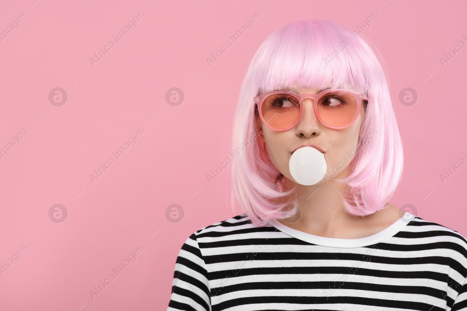 Photo of Beautiful woman in sunglasses blowing bubble gum on pink background, space for text