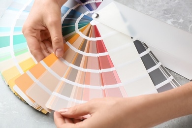 Woman with palette samples at grey marble table, closeup