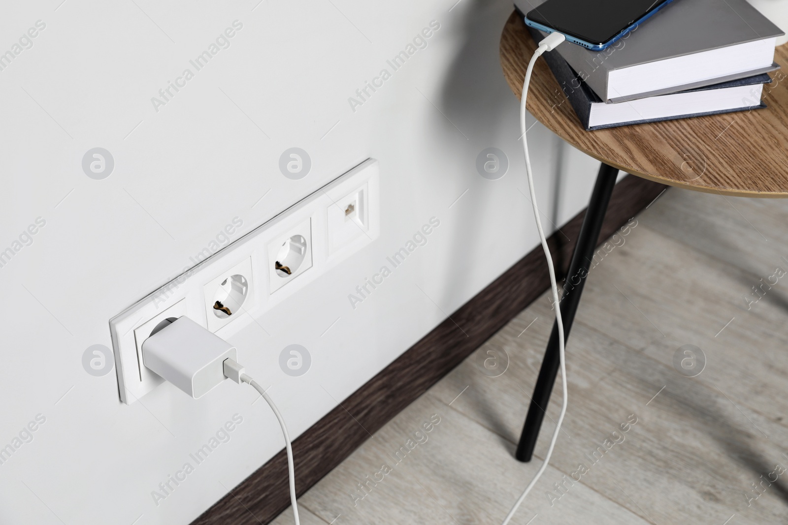 Photo of Modern smartphone charging from electric socket indoors