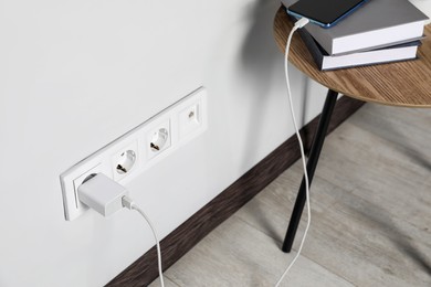 Photo of Modern smartphone charging from electric socket indoors