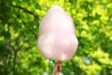 Photo of Woman holding sweet cotton candy outdoors, closeup