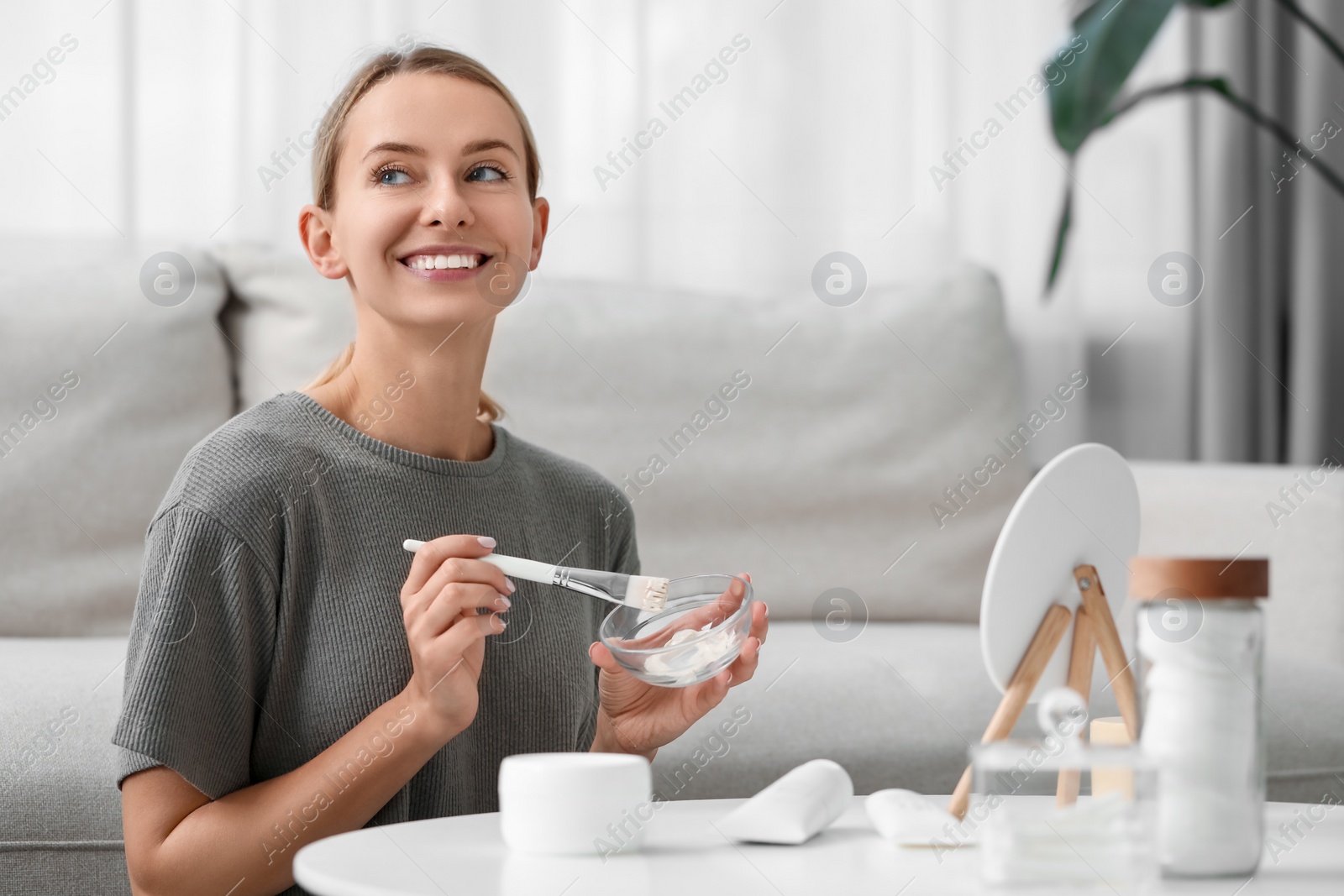 Photo of Young woman preparing face mask in front of mirror at home. Spa treatments