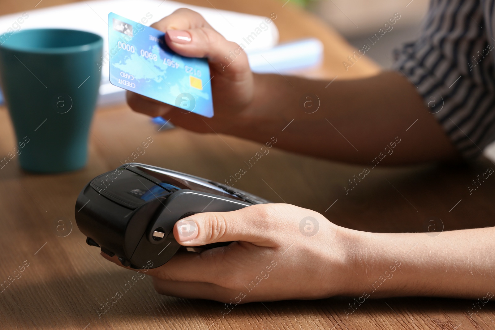 Photo of Woman using modern payment terminal at table indoors, closeup