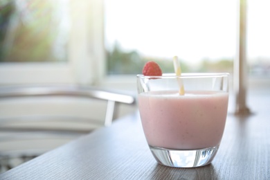 Photo of Tasty fresh milk shake with raspberry on table indoors. Space for text