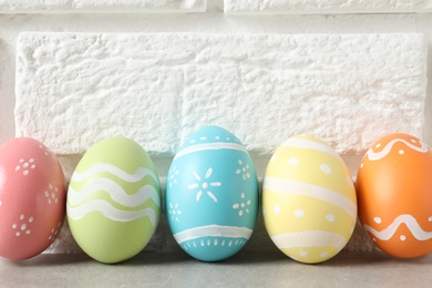 Colorful painted Easter eggs on table near brick wall, space for text