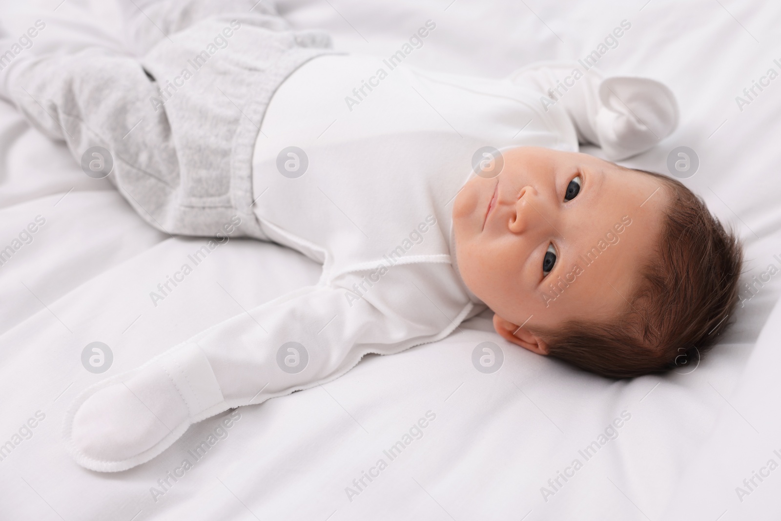 Photo of Cute newborn baby lying on white soft bed