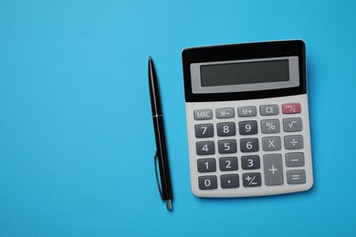 Calculator and pen on light blue background, flat lay with space for text