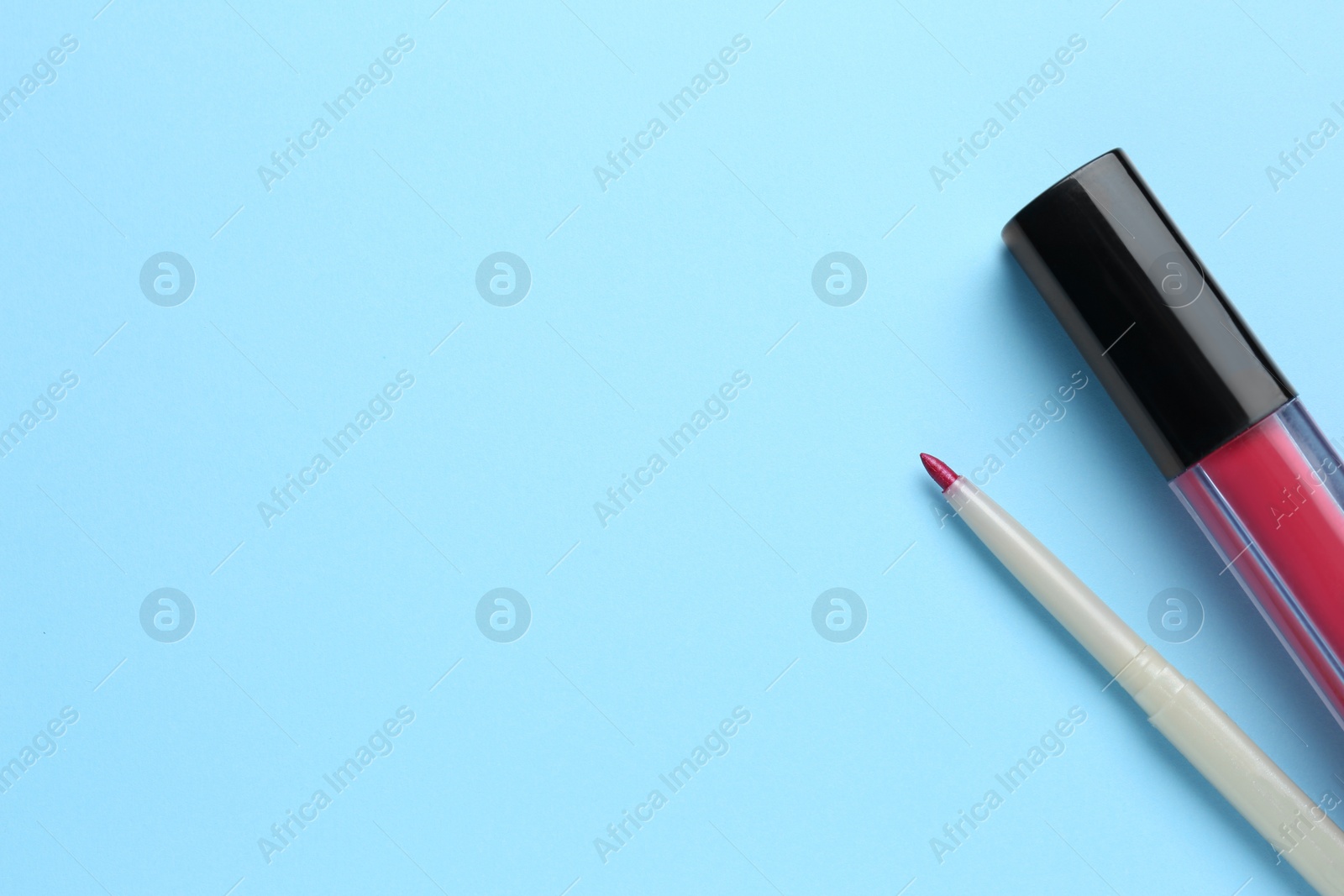 Photo of Lip pencil and liquid lipstick on light blue background, flat lay with space for text. Cosmetic product