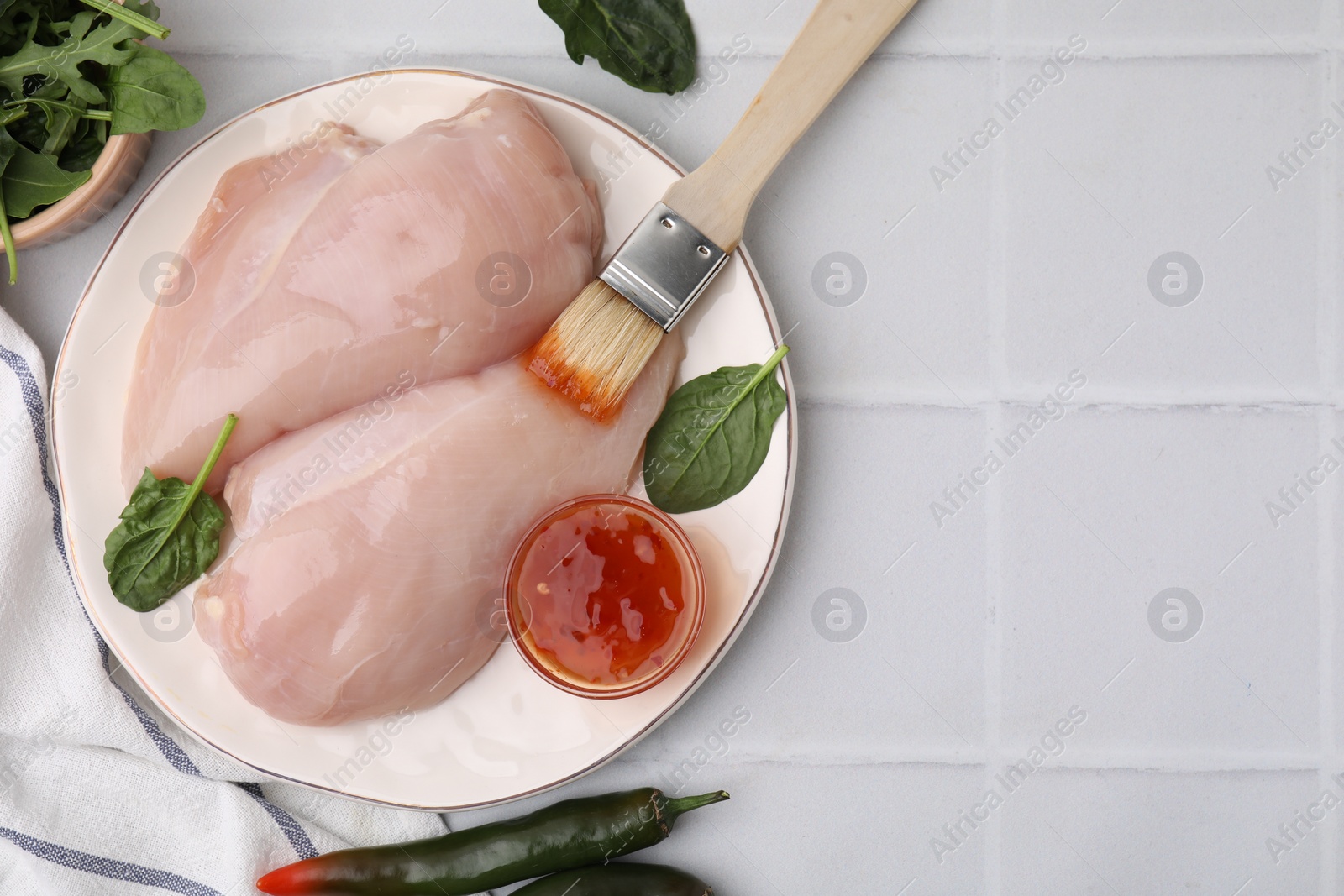 Photo of Marinade, basting brush and raw chicken fillets on white table, flat lay. Space for text