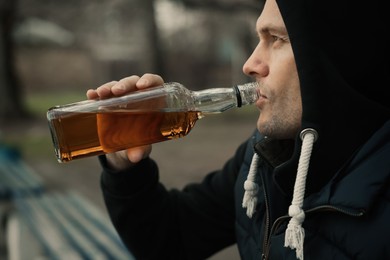 Photo of Addicted man drinking alcohol outdoors, closeup view