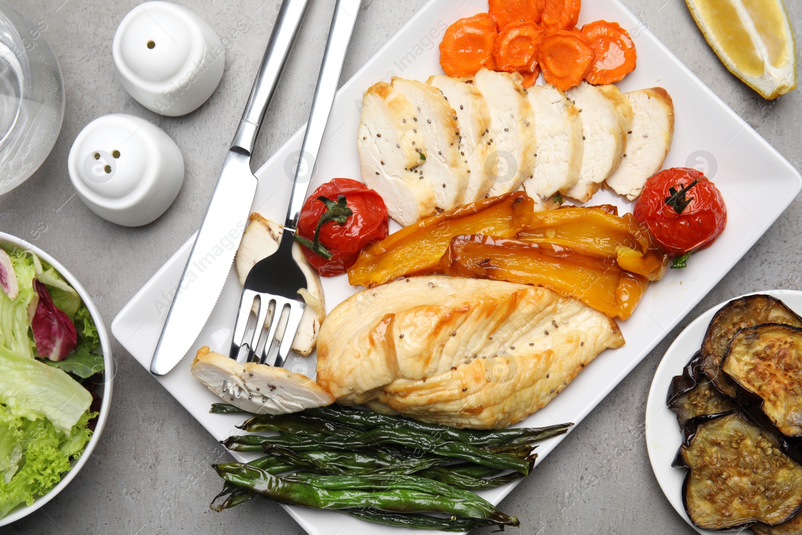 Photo of Tasty cooked chicken fillet and vegetables served on grey table, flat lay. Healthy meals from air fryer