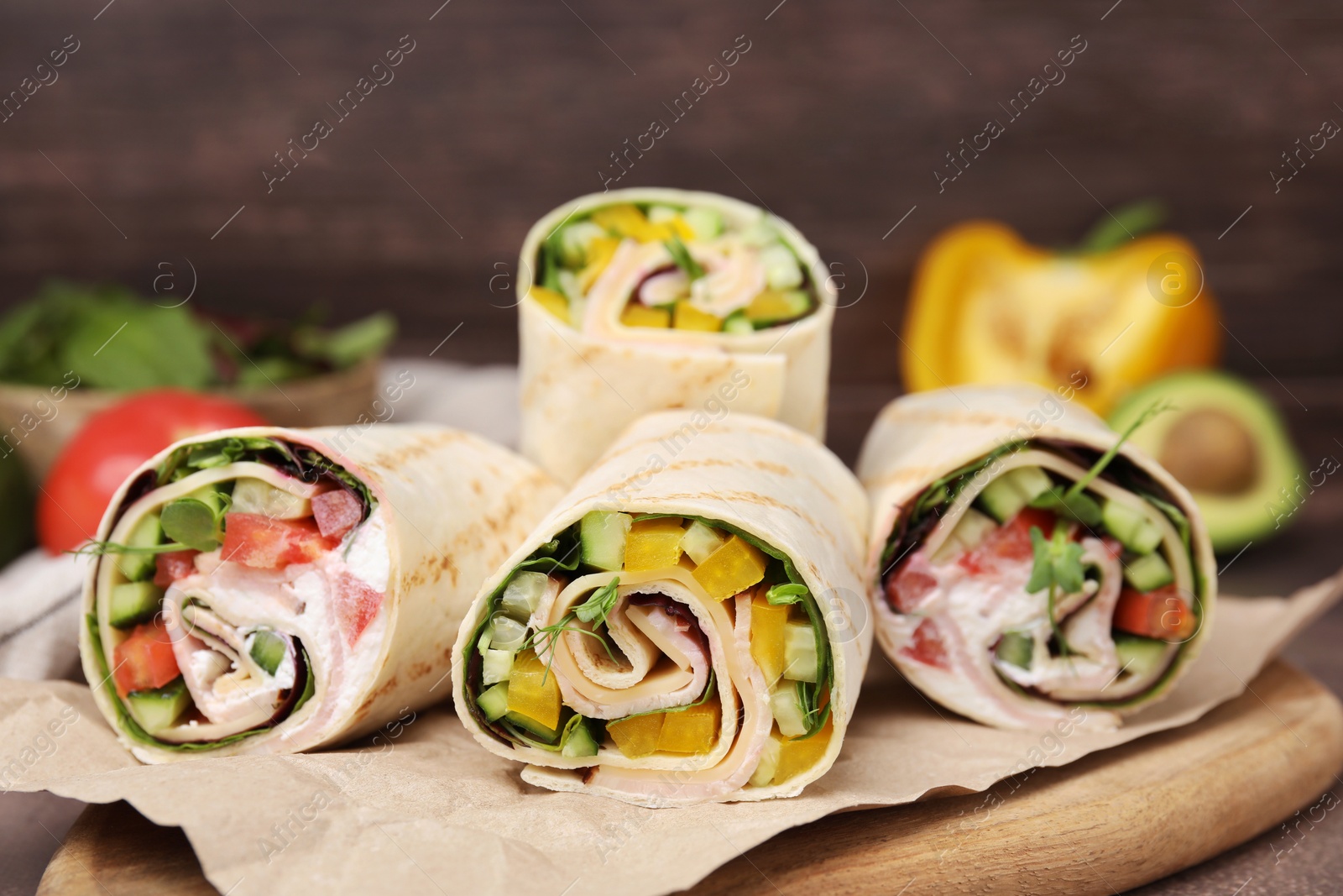 Photo of Delicious sandwich wraps with fresh vegetables on wooden board, closeup