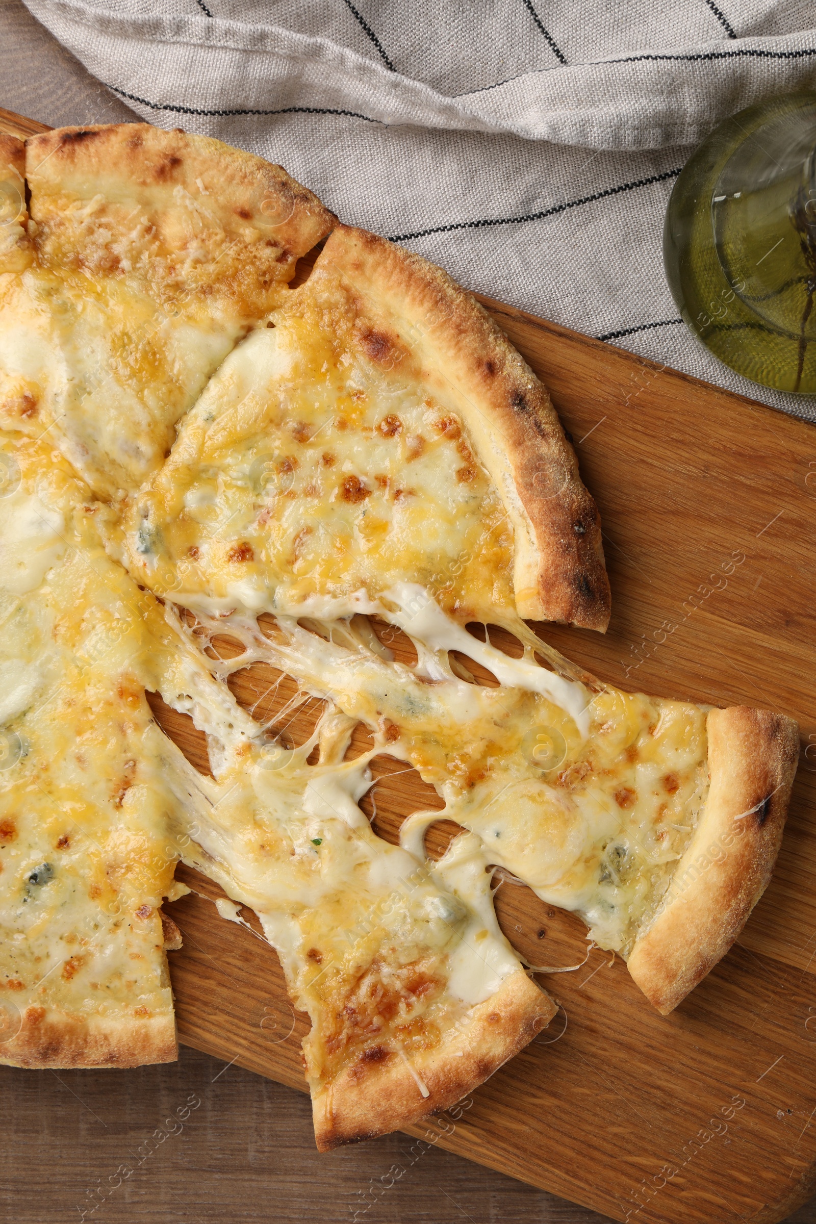 Photo of Delicious cut cheese pizza and oil on wooden table, flat lay