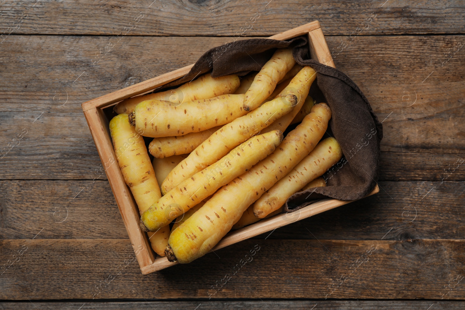 Photo of Raw white carrots in crate on wooden table, top view