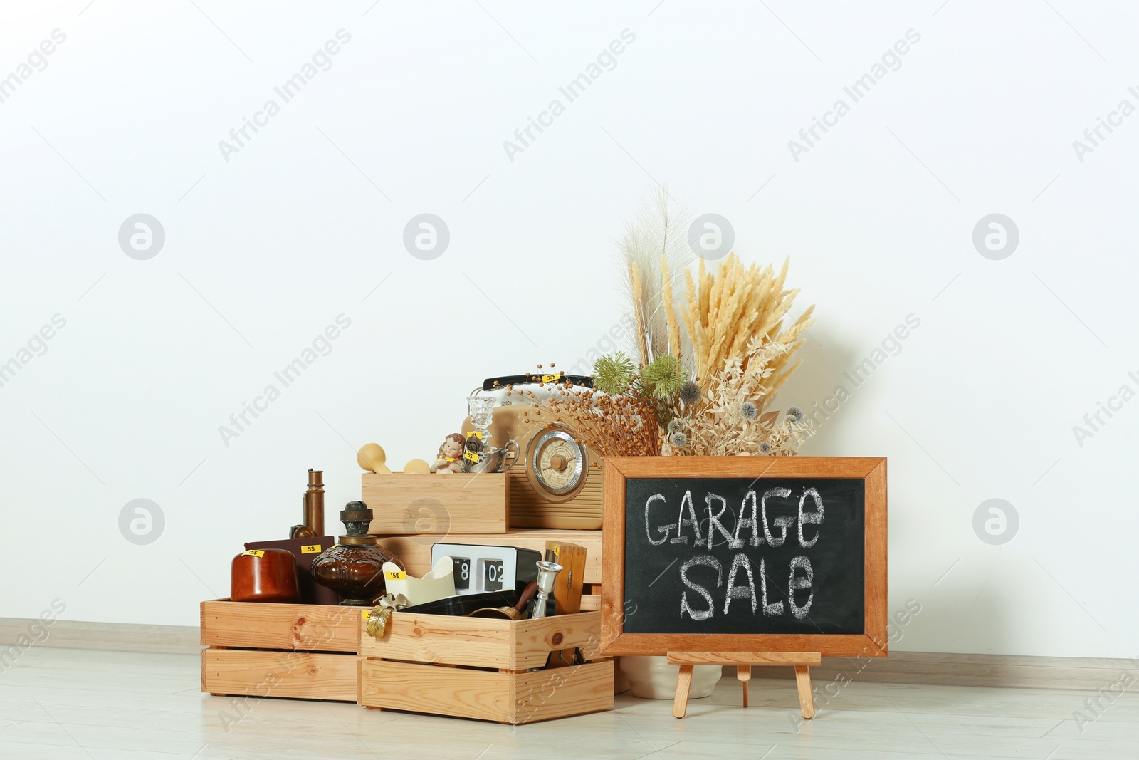 Photo of Sign Garage Sale written on blackboard and many different stuff near white wall