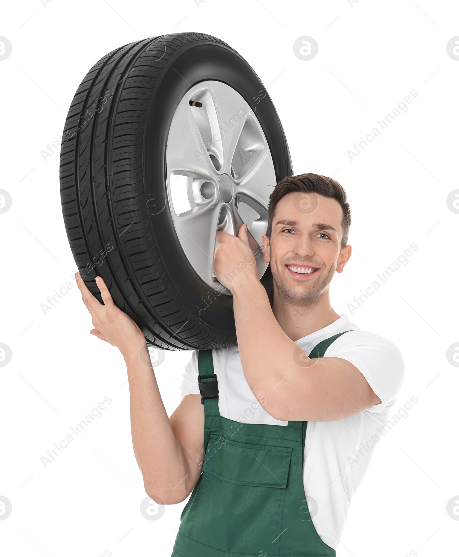 Photo of Young mechanic in uniform holding car tire on white background