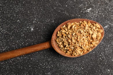 Photo of Spoon with dried orange zest seasoning on grey table, top view