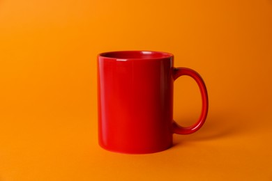 Photo of One red ceramic mug on orange background