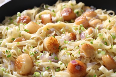 Photo of Delicious scallop pasta with onion in bowl, closeup