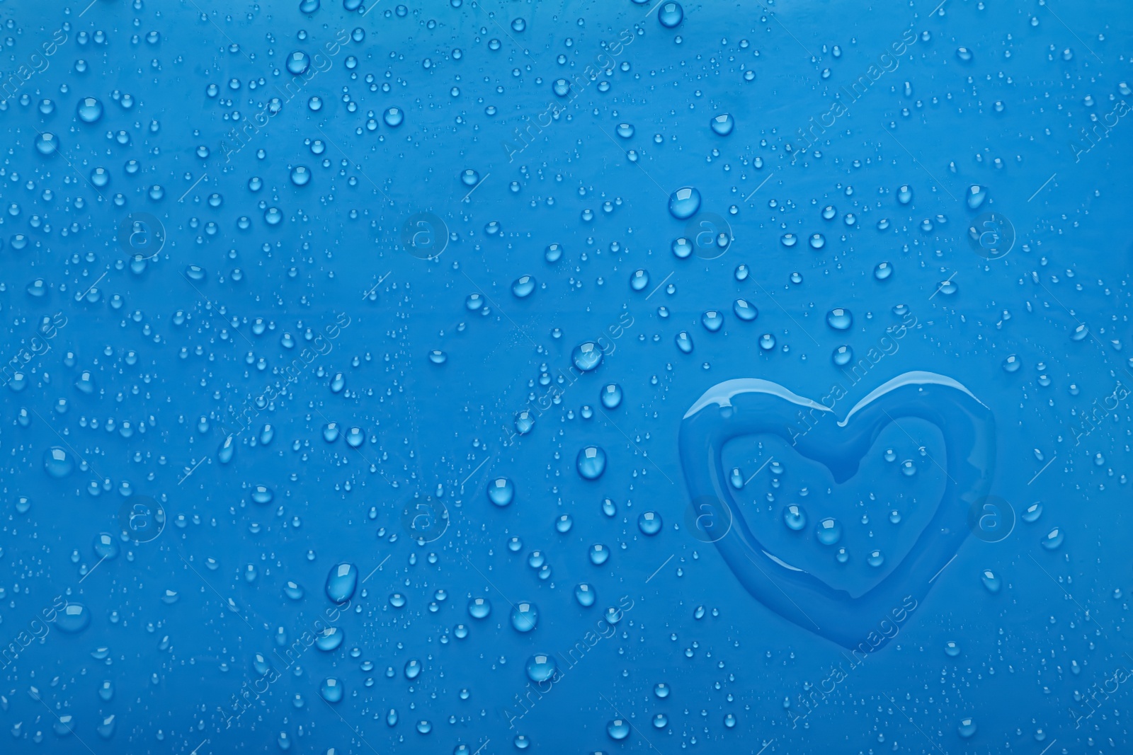 Photo of Heart shape of water and drops on blue background, top view