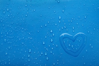 Photo of Heart shape of water and drops on blue background, top view