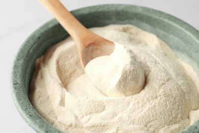 Photo of Bowl and spoon of agar-agar powder on white background, closeup