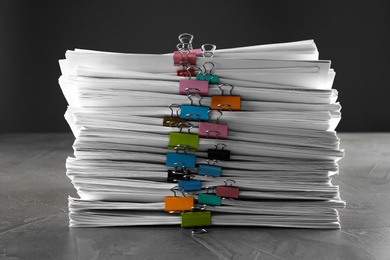 Photo of Stack of documents with binder clips on grey stone table