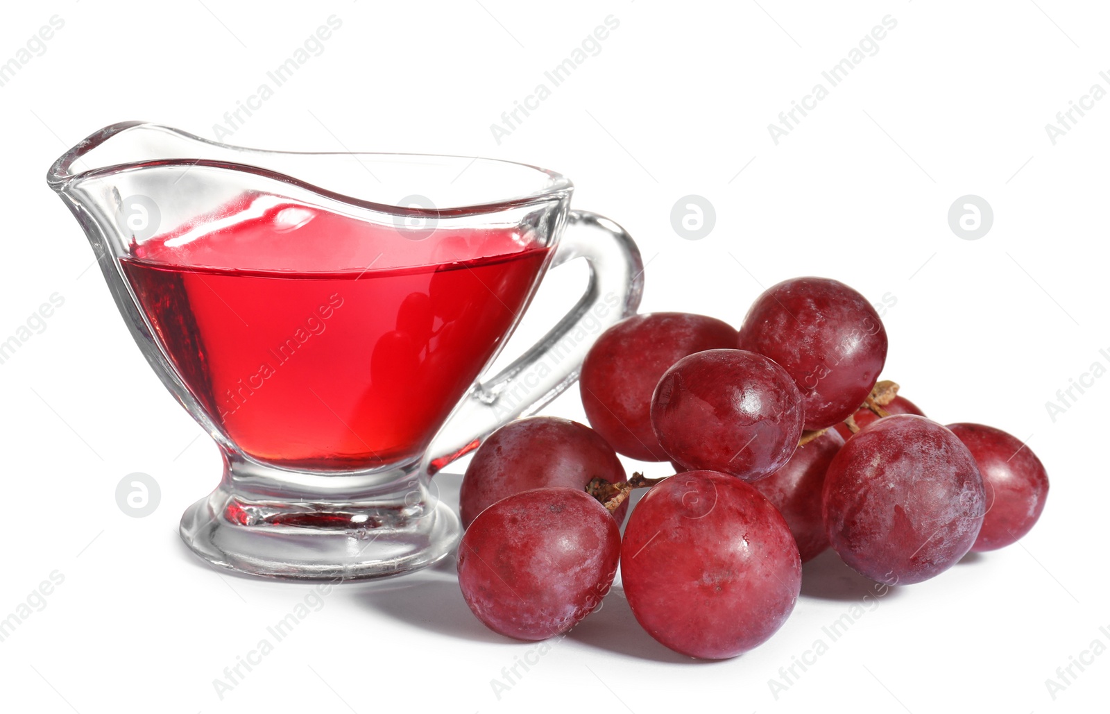 Photo of Glass gravy boat with wine vinegar and fresh grapes on white background