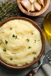 Photo of Delicious mashed potato with thyme served on wooden table, flat lay