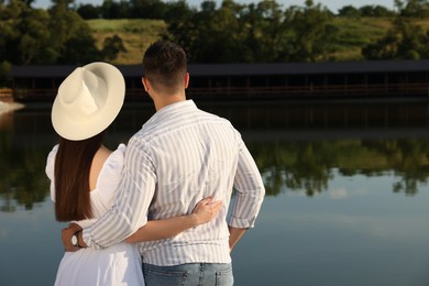 Romantic date. Couple spending time together near lake, back view with space for text