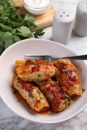 Photo of Delicious stuffed cabbage rolls cooked with homemade tomato sauce on white marble table