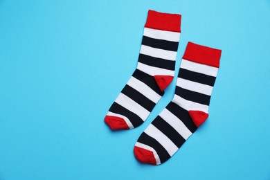 Photo of Striped socks on light blue background, flat lay. Space for text