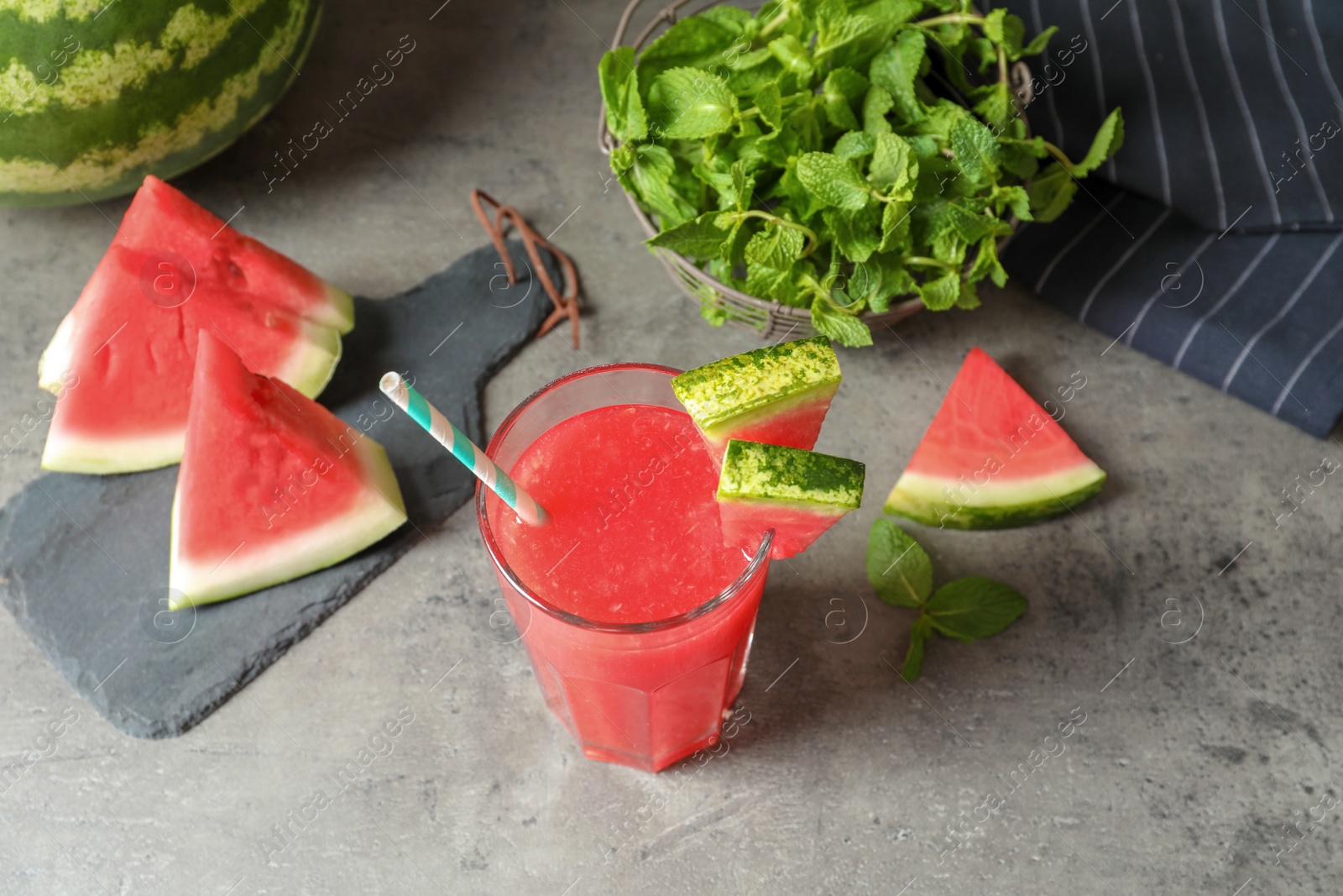 Photo of Summer watermelon drink in glass and sliced fruit on table