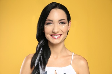 Portrait of young hippie woman with boho makeup in stylish outfit on color background