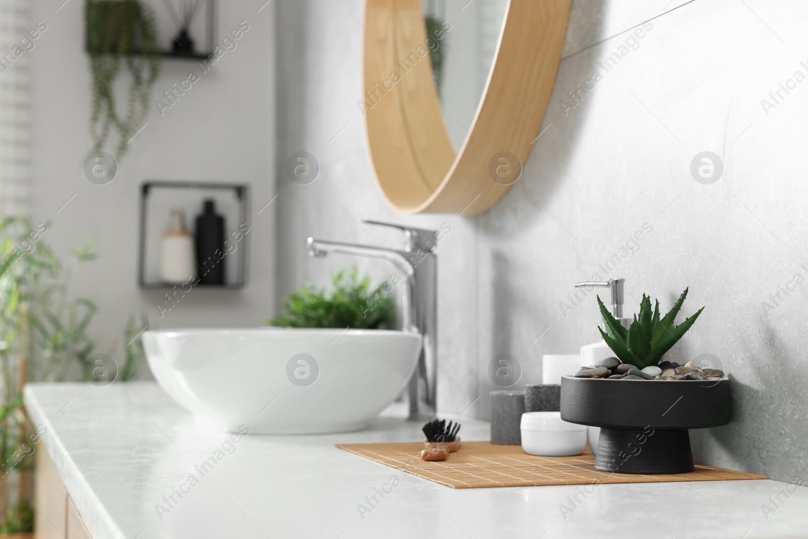 Photo of Potted artificial plants and toiletries near sink on bathroom vanity