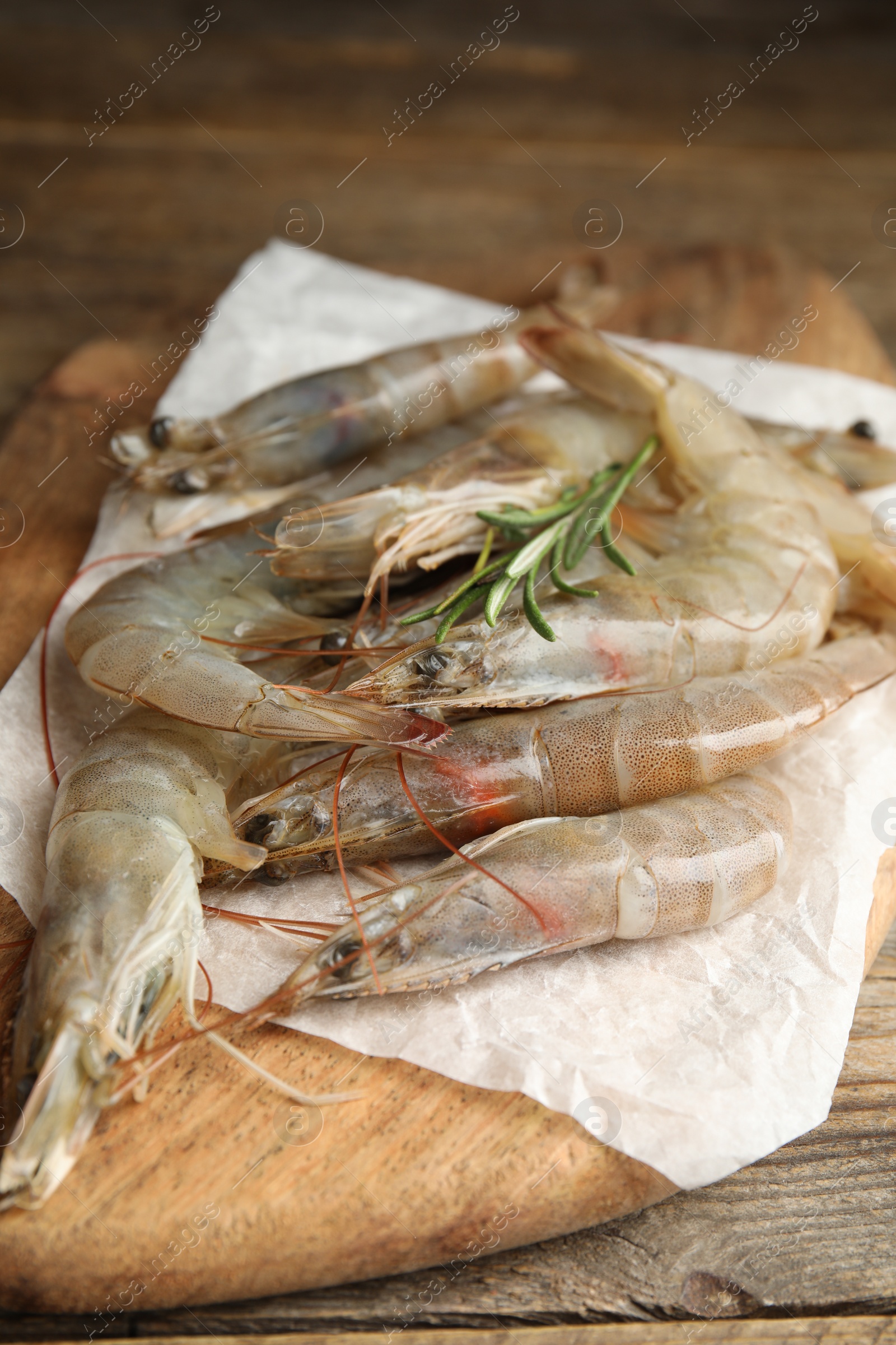 Photo of Fresh raw shrimps with rosemary on wooden table