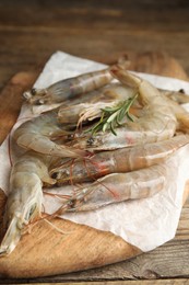 Photo of Fresh raw shrimps with rosemary on wooden table