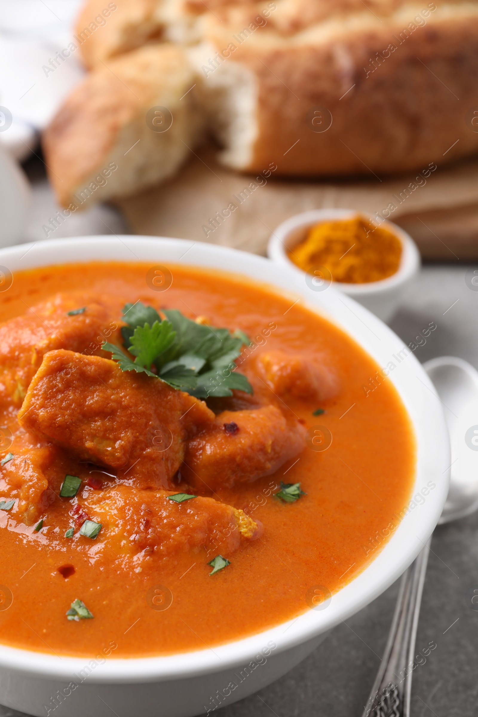 Photo of Bowl of delicious chicken curry on light grey table, closeup