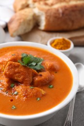 Photo of Bowl of delicious chicken curry on light grey table, closeup