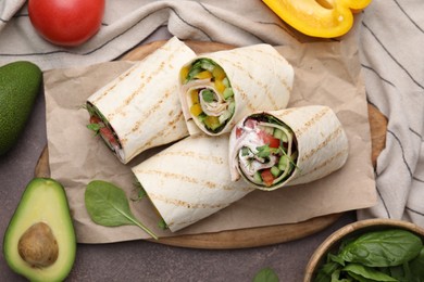 Photo of Delicious sandwich wraps with fresh vegetables on grey table, flat lay