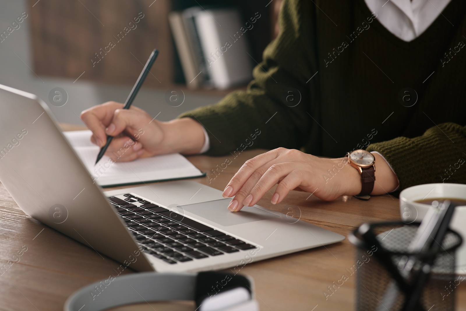 Photo of Woman with modern laptop learning at table indoors, closeup