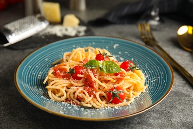 Tasty pasta with basil, tomatoes and cheese on grey table