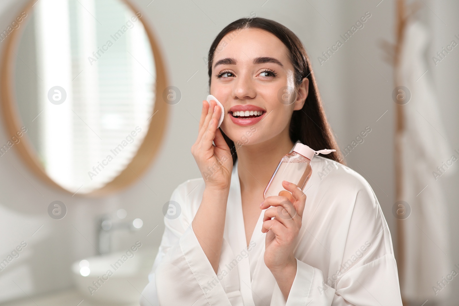 Photo of Beautiful woman removing makeup with cotton pad indoors